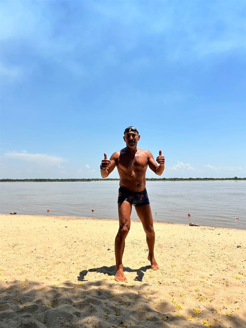 Viajero en una playa de río con los pulgares arriba