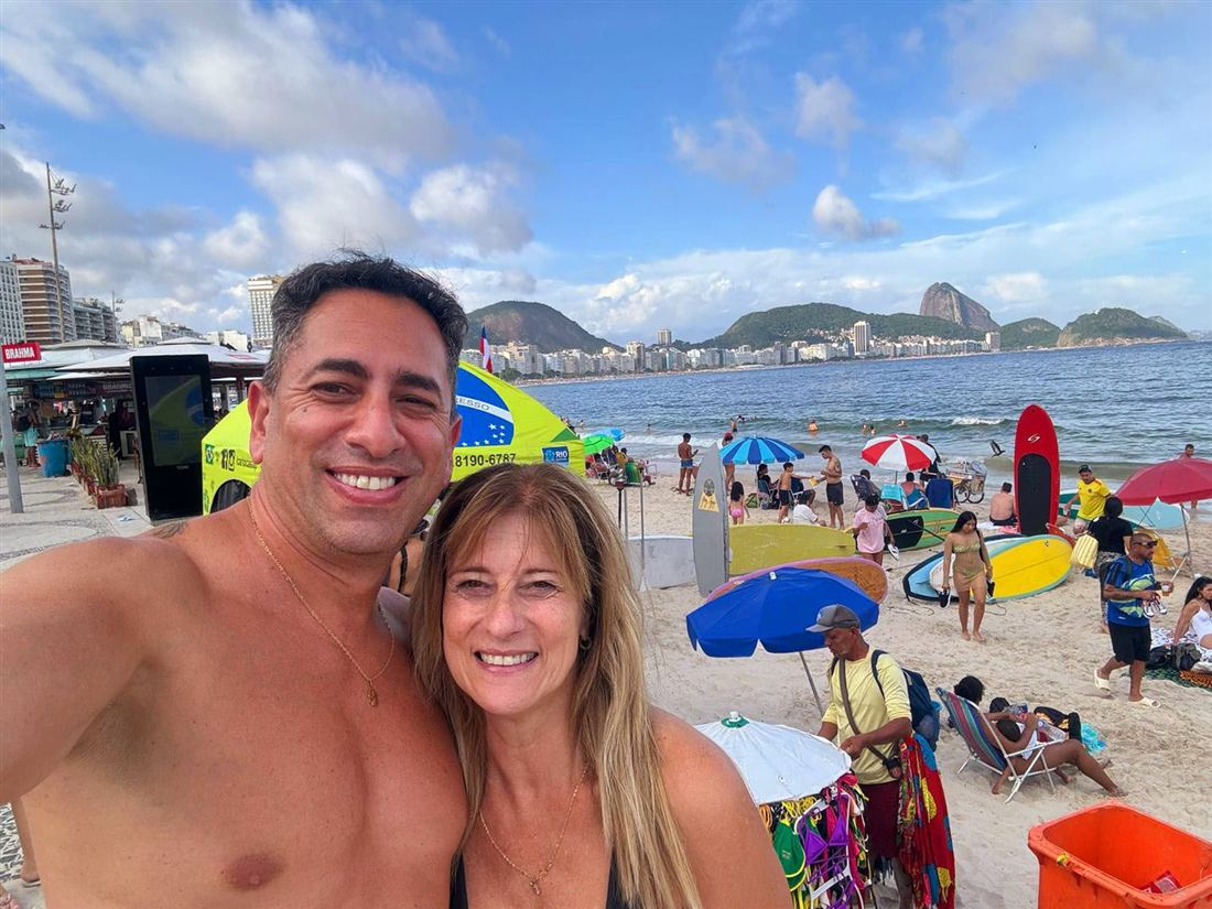 Pareja de viajeros en la playa de Copacabana con el Pan de Azúcar de fondo
